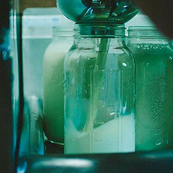 Raw milk being poured into a glass jar